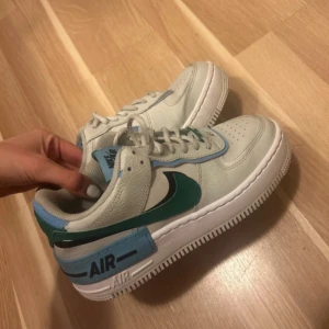 Nike Air Force  - Säljer dessa supersnygga nike air force. Använd några gånger och säljer pga för små. Färgen ska vara beigevit med gröna och blåa detaljer vilket den är.