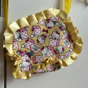 Supersöt väska med Hello Kitty-motiv. Stängs med dragkedja. Gul lång axelrem. Storlek 20x15 cm. 