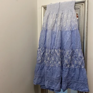 Blå långkjol med snören  - En liten fläck på snöret  Köpt på en marknad i Spanien Kjolen är 90 cm lång