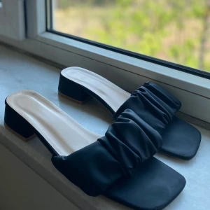 Svarta sandaler med rynkad detalj - Ett par eleganta svarta sandaler med en rynkad detalj över foten. Sandalerna har en fyrkantig tå och en låg klack, de är helt nya och använd ett par gånger. De är lite söndrig där framme men inget och vara orolig för.