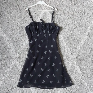 Svart klänning med fjärilsmönster från H&M Divided - Svart somrig klänning med smala axelband och ett fjärilsmönster i vitt. Mycket bra skick och säljer då den är för liten för mig.