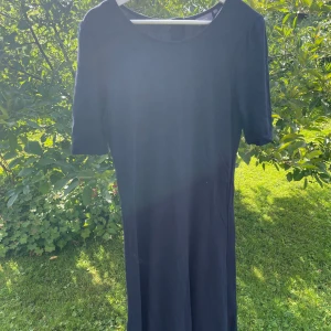 Blå klänning - Blå figursydd klänning i smickrande modell. Dragkedja bak, en kort bit ner. Markerad midja med söm och något klockad kjoldel. 88% viskos, 10% polyester, 2 % elastane.