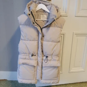 Vadderad väst - Oversize. Dragsko i midjan och huva. 