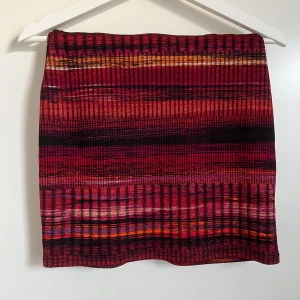 Fin kjol - Väldigt fin kjol som är använd ett fåtal gånger, nästan nyskick, huvudgärden är röd men med nyanser av lila, orange och guld, tight passform