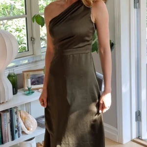 Fest klänning - Olivgrön one shulder klänning lite längre skurning baktill en framtill använd 1gång. Snyggt fall. 