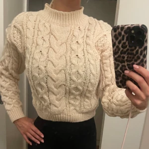 Vit stickad tröja - Kabelstickad vit/beige tröja, lite kortare modell som slutar lite över rumpan, sitter fint på men används inte då jag har många liknande