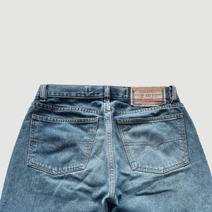 Diesel - Raka Jeans - Storlek 31 - VARAN KAN KÖPAS DIREKT PÅ VÅR HEMSIDA, ettmarke.se MÄRKE: Diesel Industry. MODELL: Raka. FÄRG: Blå. STORLEK: 31 enligt lapp. MIDJA RAKT ÖVER: 40 cm. MIDJEHÖJD: 24 cm. TOTALLÄNGD (FRÅN MIDJAN): 102 cm. BENLÄNGD (FRÅN INNELÅRET): 78 cm. 