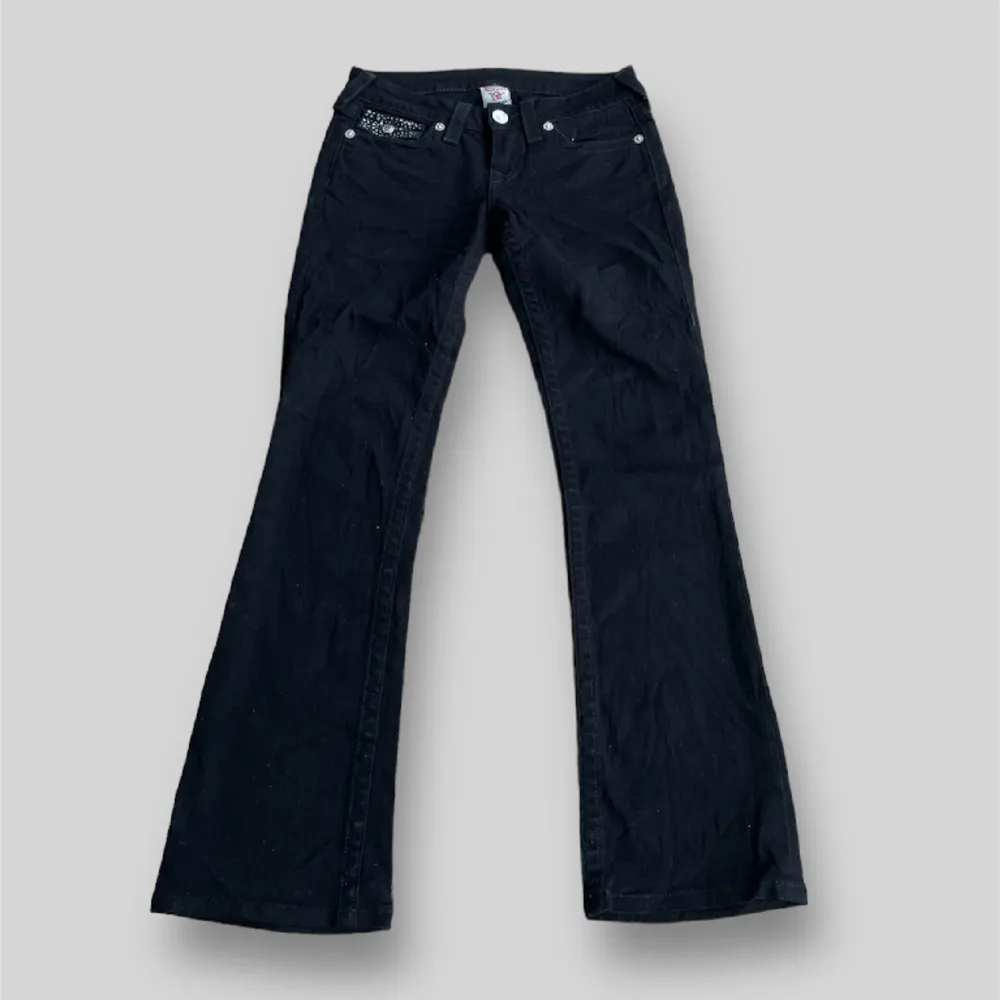 Svarta true religon jeans med stenar på fickorna i modellen Hi-Rise boot, fint skick inga tecken på defekter, tagg: storlek 26. Ytterbens längden är ca 94cm och midjan är ca 36cm rakt över, tveka inte på att kontakta vid minsta fundering!. Jeans & Byxor.