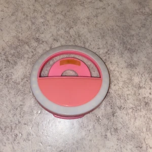 Liten selfie/video lampa  - En liten ramla som ska fästas på telefonen vid kameran. Det ger bilderna och videorna extra bra belysning)
