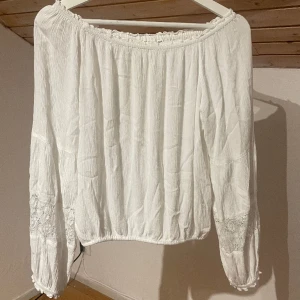 Fin off shoulder blus - En fin vit off shoulder blus med blommig dekor på ärmarna, inga fläckar bra skick och knappt använd. 