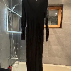 En svart stretchig klänning med en slits vid en knät.