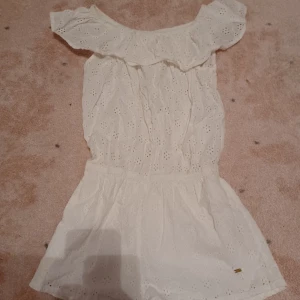 Jättesöt vit mönstrad byxdress jumpsuit med volang upptill  - Säljer denna supersöta vita byxdressen med mönster på. Den är knappt använd så skicket är perfekt! Den har volang upptill så man kan ha den både off shoulder och on shoulder. Storlek 158 men passar mig som brukar ha xs eller s.Köpare står för frakten