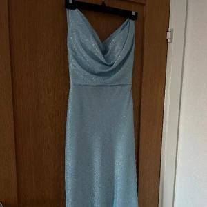 Balklänning ljusblå - Säljer min fina ljusblåa glittriga balklänning som endast är använd under 2 timmar. Klänningen är köpt på weddingstore för 2500kr och resegarderob medföljer. Den har en öppen rygg med korsade band och smala axelband💖 tveka inte att höra av dig! 