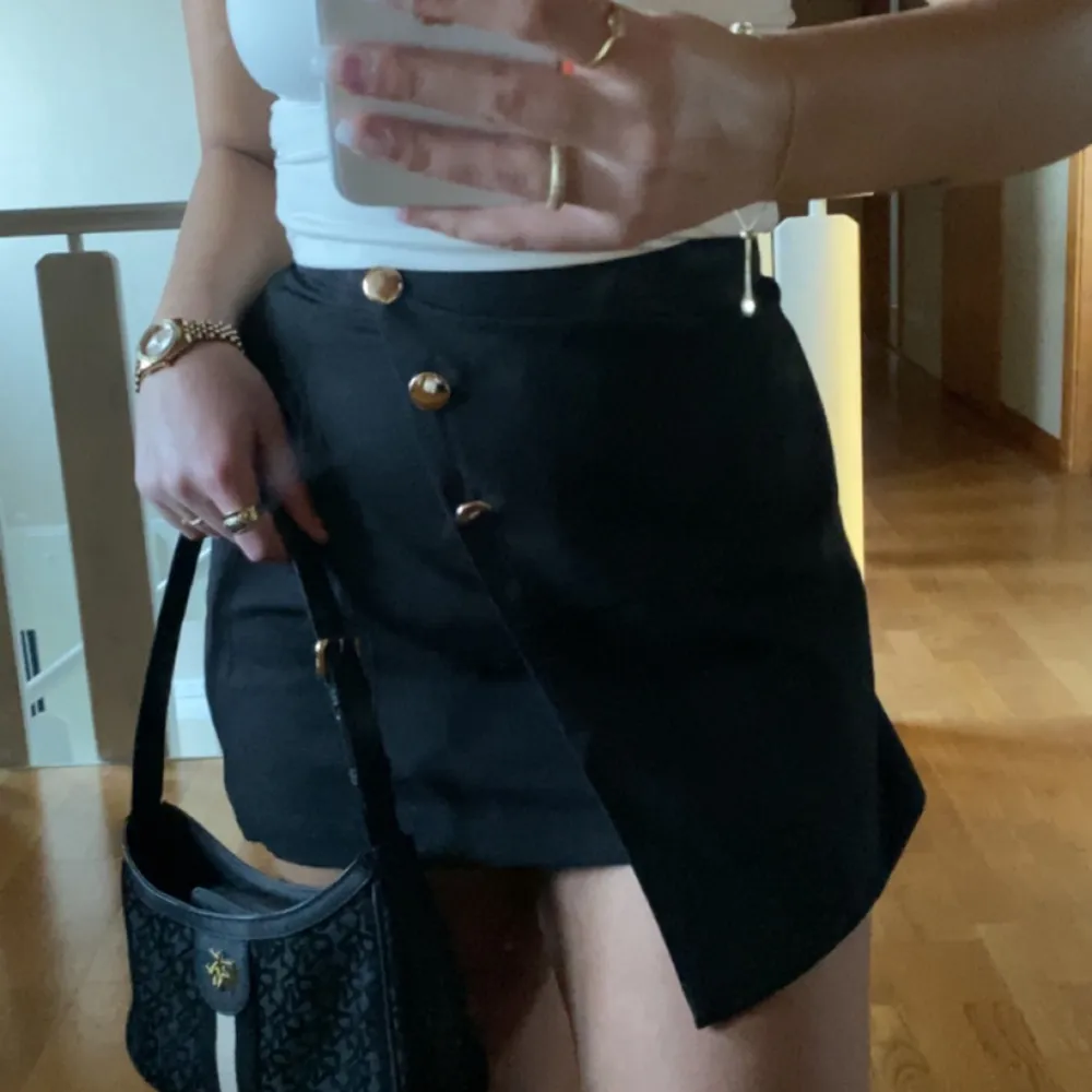Säljer denna söta svarta kjol som har shorts under!🙌🏼🐚 Gulliga guldknappar på Använd fåtal gånger Fint skick!!. Kjolar.