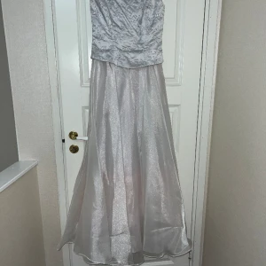 Dave and johnny balklänning  - Balklänning i silver med knyten rygg och plaketter på korsetten. Storlek S 