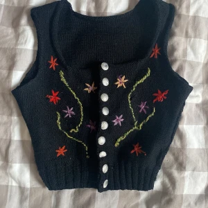 Stickad Väst - En stickad väst med blommor. Snäckformade knappar i silver. Köpt secondhand. Inget märke eller storlek. 