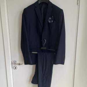 Marinblå kostym i nyskick från butiken Jezz i Kalmar, använd endast 1 gång. Näsduk och skyddsfodral tillkommer samt nyligen kemtvättad.  Storlek EU 48, motsvarar M