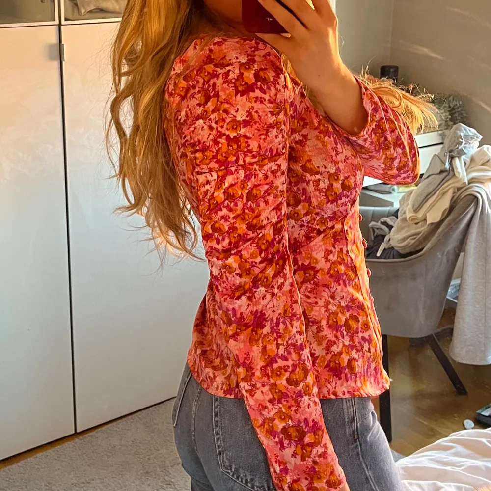 Blus i rosa lila orange, figursydd med knappar fram till. Blusar.