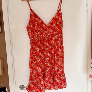 Blommig sommarklänning - Fin V-ringad sommarklänning med röda och vita blommor 🌻 Stl L med justerbara straps. Volang längst ned 💓