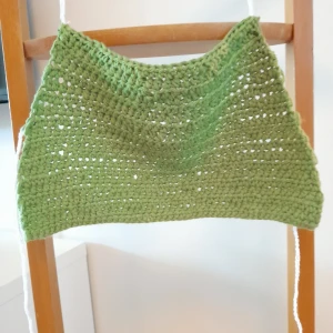 Grön virkad topp - En handgjord grön virkad topp med en enkel design. Toppen har en vit knytning backtill och är ärmlös.