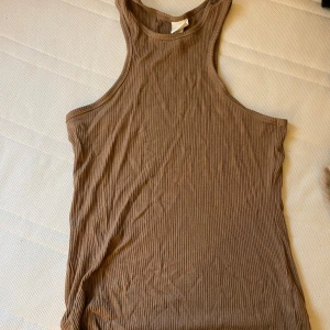 Beige ribbad linnetopp från H&M - En beige ribbad linnetopp från H&M. Toppen är ärmlös och har en rund halsringning.