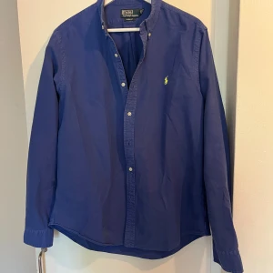 Ralph lauren skjorta - Säljer denna fina skjortan från Ralph lauren då den fått snålt med användning. Fin blå färg med neon gult märke. Storlek L, passar mig bra som är 189cm, 65kg. 