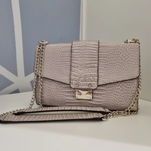 Axelremsväska från Guess  - Jätte fin och helt ny Handväska som jag köpte för två år sen men helt oanvänd och med taggen kvar. Remmen på väskan kan justeras och användas både kort och lång Originell pris är 1500 sek 