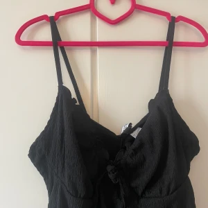 Svart figurformad klänning - Snygg svart klänning som ska sitta figurnära med en knytning. Originalpris 100kr.