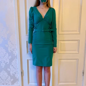 Grön klänning, Emmy design  - Jättefin grön tajt klänning i skönt material. Storlek M. Kommer med ett justerbart skärp Modellen på bilden är 173 cm och har storlek 38 i de flesta andra kläder. Aldrig använd. Vi har lagt ner vår klänningsbutik och säljer ut. Ny pris är 2000-3000kr