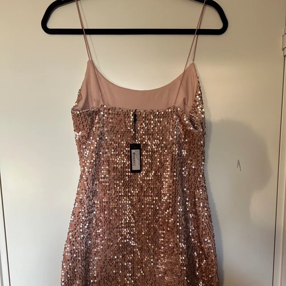 Helt ny jätte fin paljettklänning från Nelly, säljs för den inte kommer till användning, storlek M, färgen är rosa/champagne . Klänningar.