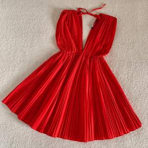 Superfin röd plisserad klänning från ZARA med v-ringning. Använd i några timmar endast, utan anmärkningar. I nyskick. Stretchig passform, passar XS-M.