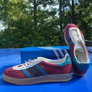 Adidas Gazelle Indoor Collegiate Burgundy - Helt nya och aldrig använda! Orginallåda samt kvitto finns. Säljer dem då jag köpte för stor storlek. Dessa skor är ovanliga och svåra att få tag på till samma pris i Sverige.  De passar otroligt bra till det mesta och funkar som statement piece.