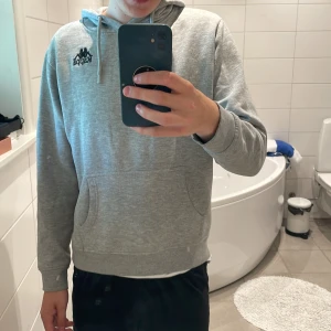 Hoodie - Säljer en grå hoodie från märket Kappa. Skicket på tröjan är nästintill perfekt förutom en liten fläck på armen som man ser på bild 2