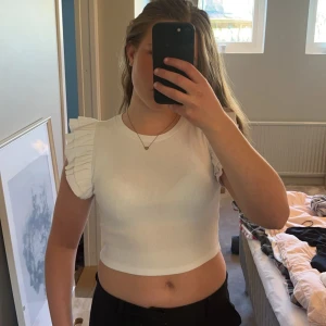 Vit topp zara - En vit topp med små volanger på ärmarna, från zara. Använd ett fåtal gånger och därför i mycket bra skick. Jättefin nu till sommaren!