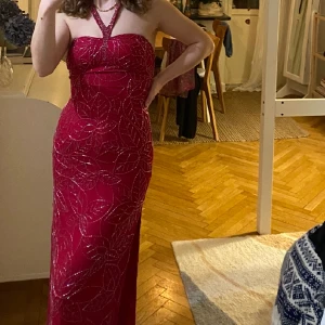 Röd balklänning med pärlbroderi - Säljer med sorg denna balklänning då den blivit för liten. Fint skick, och finns extra pärlor ifall någon skulle ramla av. 