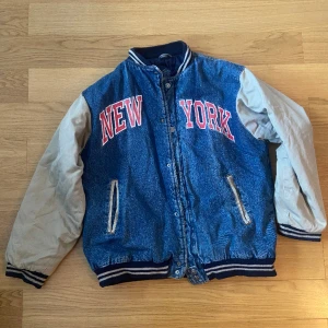 College jacka!  - Snygg College jacka med trycket ”New York”. Väldigt skön lite overzised. Köpt begagnad men i väldigt bra skick! Jeans tyg, beiga armar och fodrad! 