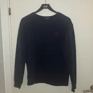 Mörkblå sweatshirt med rött märke på bröstet. Har krympt i tvätten till ungefärlig M/S storlek.