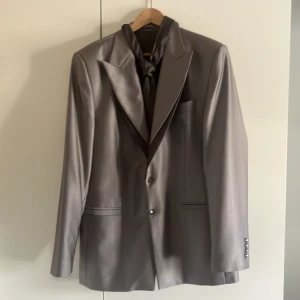 Kostymsett silverfärgad (nyskick) - Kostymsett i storlek 52 där alla delar är i nyskick. Färgen är Silver. Det som ingår är: -Kostym -Kostymbyxor  -Kostymväst -Slips