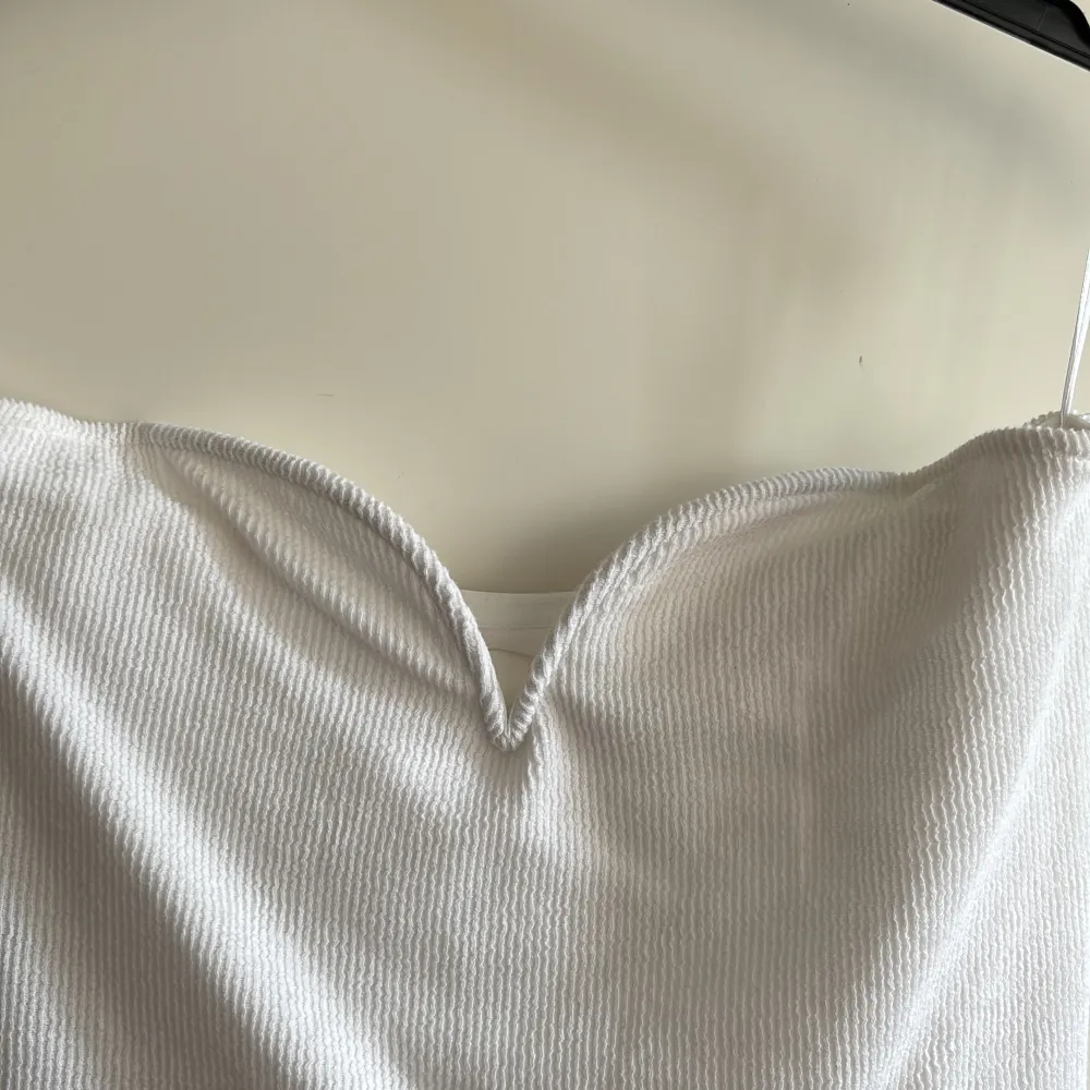 Vit kort klänning med en vacker detalj vid bröstet! (I bilden är den svart och det är samma klänning fast i vit som jag säljer, bilden är till för att visa hur den sitter på!)♥️. Klänningar.