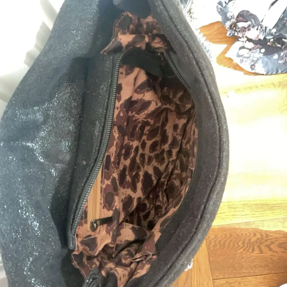 En fin alex väska som är glittrig och har leopard mönster innuti med kedja. Väskor.