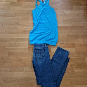 Jeans och blå topp - Ett par lågmidjade jeans med tillhörande blått linne i längre modell.