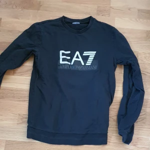 EA7 Emporio Armani Sweatshirt i svart - Storlek M Regular fit Rätt så tunt material och är i bra skick. Använts få gånger, ca 1-5 gånger