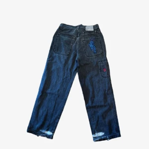 JNCO Jeans - Färgen är som på närbilden av trycket! Baggy jeans med cool detalj på bakfickan, tyvärr finns lite slitage från skejting vid hälarna. 