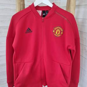 Ziptröja från Adidas, skick som ny. Manchester United tryck på ryggen och emblem på bröstet.