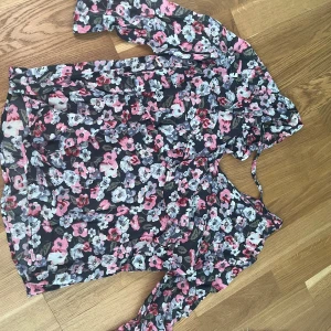 Blommig blus med volang storlek s  - Volanger fram och bak  Band i rygg  V-ringad bak & framtill 