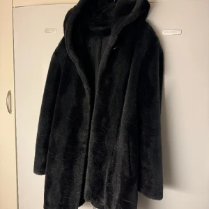 Pälskappa - Super mysig pälskappa som är Perfekt till vintern samt kanske kall höst! Den är inte äkta päls och färgen är som mörkgrå/svart. Storleken skulle jag säga är S/M/L + en stor mysig luva. Hör av er vid frågor🩷