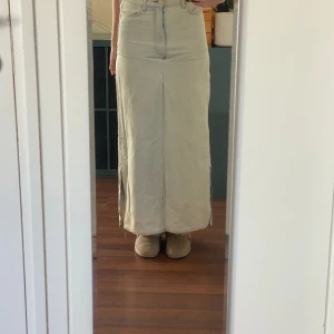 Lång jeanskjol  - Lång jeanskjol med slits vid sidan. Storleken är 36 och är ursprungligen från hm. Finns tyvärr några ljusgula fläckar baktill, har inte tänkt på dessa innan men dem existerar. 