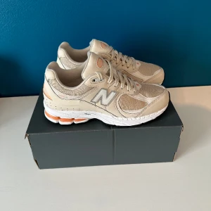 New Balance 2002R  - Helt nya beiga sneakers från New Balance 2002R. Köpta på JD sports. Nypris 1650:-, mitt pris 850:-. Köparen betalar frakten.