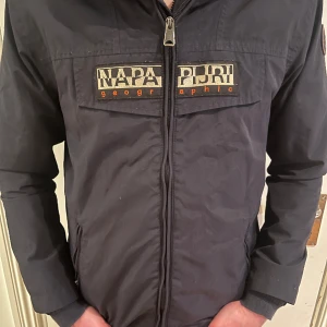 Napapijri windbreaker - Tjenare, säljer nu min napapijri windvreaker eftersom att den var för liten(trodde den va M men de va S) nypris är typ 1500-3000kr beror på vart man köper den. Den är helt vattentät och den är använd i typ 2 veckor. Den är marinblå inte svart.