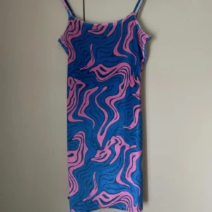 Mönstrad kort klänning - Blå och rosa mönstrad klänning i sammetsliknande material på utsidan💗 Använt fåtal gånger och jättefint skick!☺️